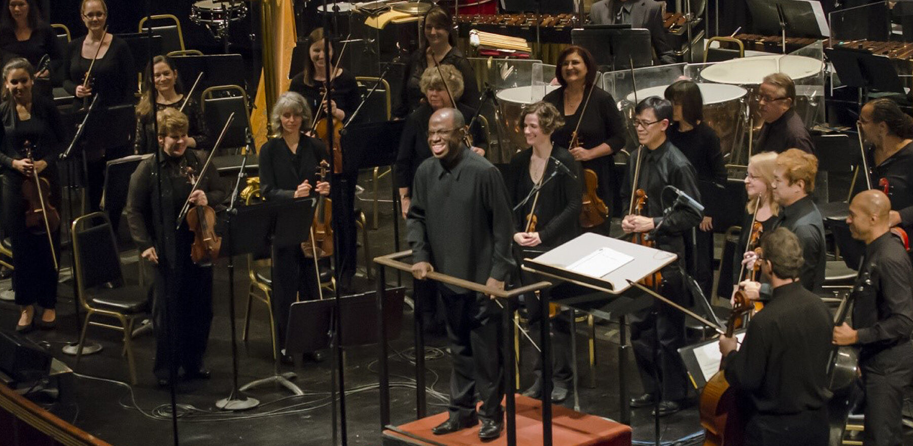 Michael Morgan standing on stage with the Oakland Symphony Orchestra